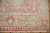 Distressed texture of a vintage Oushak rug with faded blush pink and ivory patterns, and visible foundation.