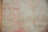 Secured side of distressed Oushak runner, with faded blush and powder blue patterns.