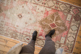 Distressed Oushak runner, showcasing its faded blush, ivory, and bronze geometric motifs.