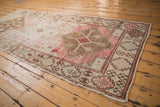 Distressed Oushak runner, serrated medallion, pale blush, bronze, geometric floral motifs.