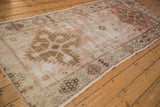 Distressed vintage Oushak runner edge, revealing faded blush, ivory, and bronze floral geometrics.
