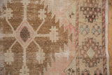 Distressed Oushak runner detail: geometric plants in pale blush, ivory, bronze, with visible knot heads.