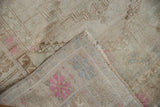 Distressed Oushak rug corner shows soft, short pile, muted pink patterns, hand-knotted reverse.