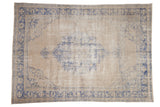 Vintage distressed Oushak carpet with a faded blue medallion and border on an antique ivory field.