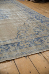 Mostly even wear across the beige and blue pile of a vintage distressed Oushak carpet.