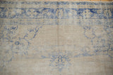 Mostly even wear across the distressed pile of a hand-knotted Oushak in beige and blue.