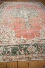 Distressed Sparta carpet with dusty terra cotta field, faded floral sprays and deep green border.