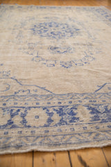 Distressed vintage Oushak pile showing even wear, blue patterns on a beige field.