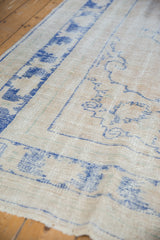 Distressed vintage Oushak carpet detail, showing worn pile, visible foundation, ivory and blue.
