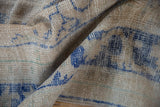 Distressed Oushak carpet detail, showing worn pile texture and cobalt blue motifs.