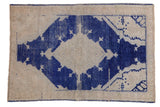 Distressed vintage Turkish Oushak rug featuring a cobalt blue medallion on an ivory abrashed field.