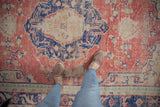 Distressed Oushak rug with faded brick red and navy colors, showing worn texture.