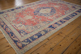 Distressed corner of vintage Oushak carpet, faded brick red, navy blue, and ivory patterns.