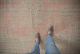 Textured distressed Oushak carpet showing worn rose pink, mint, and ivory pile.