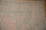 Distressed Oushak rug corner, showing rose pink and pale mint green floral spandrel.