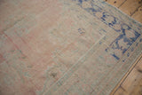 Distressed vintage Oushak rug corner with faded rose, mint, and cobalt blue motifs.