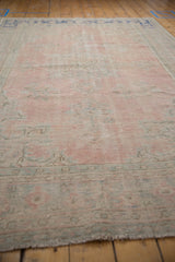 Distressed vintage Oushak carpet pile detail: faded rose pink, mint green, visible foundation.