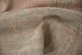 Distressed vintage Oushak carpet pile showing wear, rose pink, and pale mint green.
