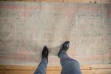 Distressed vintage Oushak runner showcasing worn texture, faded pale pink, ivory, and seafoam Rococo motif.