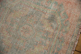 Distressed Oushak rug runner's worn pile, revealing pale pink, seafoam green, ivory tones.
