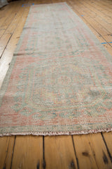 Faded Rococo patterns and worn pile detail on a distressed vintage Oushak runner with fringe.