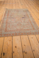 Distressed vintage Sivas rug corner with worn pile, short fringe, and muted terra cotta border.
