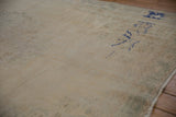 Distressed Oushak carpet pile with ivory field, faded patterns, and cobalt blue markings.