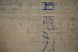 Oushak rug corner showing distressed ivory pile, slate green border, and cobalt blue motifs.