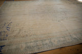 Distressed ivory Oushak carpet showing abrash, wear, and faded slate green blue border.