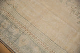 Evenly worn beige pile with faded green-blue border patterns on a vintage Oushak rug.