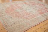 Distressed Oushak carpet with worn texture in faded dusty rose and ivory hues.