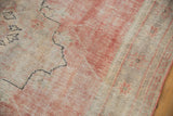 Worn pile and faded texture of the vintage Oushak rug's dusty rose field.