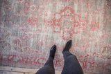 Distressed vintage Oushak rug with faded cherry red floral sprays and visible wear to the foundation.