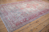Faded cherry red geometric floral motifs and distressed pile texture on vintage Oushak rug.