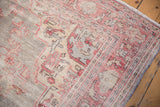 Worn pale cherry red and silver geometric floral sprays on distressed vintage Oushak rug.
