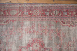 Distressed texture and faded cherry red geometric floral motifs on a vintage Oushak rug.