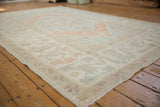 Corner of vintage distressed Oushak rug: soft pile, cloudband border, floral pinwheel, seafoam.
