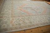 Distressed vintage Oushak rug texture with muted ivory, seafoam, and terra cotta motifs.