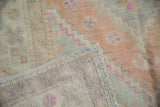 Distressed Oushak rug corner with soft pile in terra cotta, seafoam, and blue selvage.