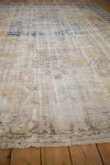 Angled view of distressed Oushak rug, showing faded beige and blue tones, exposed foundation.