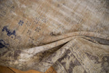 Folded vintage Oushak rug displaying distressed pile with muted beige and faded blue patterns.