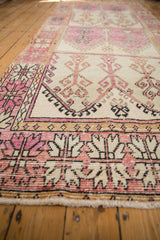 Low angle view of a distressed Oushak runner's even, low pile and geometric palmette border design.