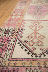 Angled detail of the worn pile and geometric hook motifs on a vintage Oushak runner.