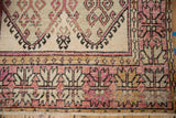 Detail of a wide-banded border with geometric serrated palmettes in aubergine, charcoal, and ivory.