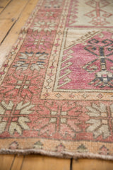 Angled close-up of a distressed Oushak runner's low pile and geometric serrated palmette border.