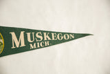 Vintage green felt pennant with cream 'MUSKEGON MICH.' lettering and texture.