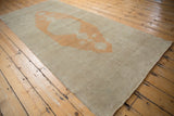 Angled view of a distressed Oushak runner highlighting the pale orange medallion on its open ivory field.