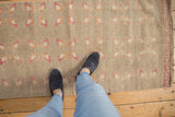 Distressed Turkish Oushak runner displaying faded raspberry, orange, ivory floral patterns.
