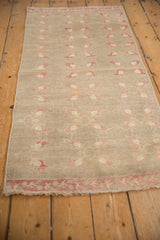 Distressed pile texture on a vintage Oushak runner, highlighting pink floral motifs and faint foundation.