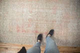 Distressed Oushak rug surface, showing textured pile wear with pale pink, silver, and ivory.